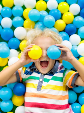 Child playing in colorful ball pit at jungle gym.