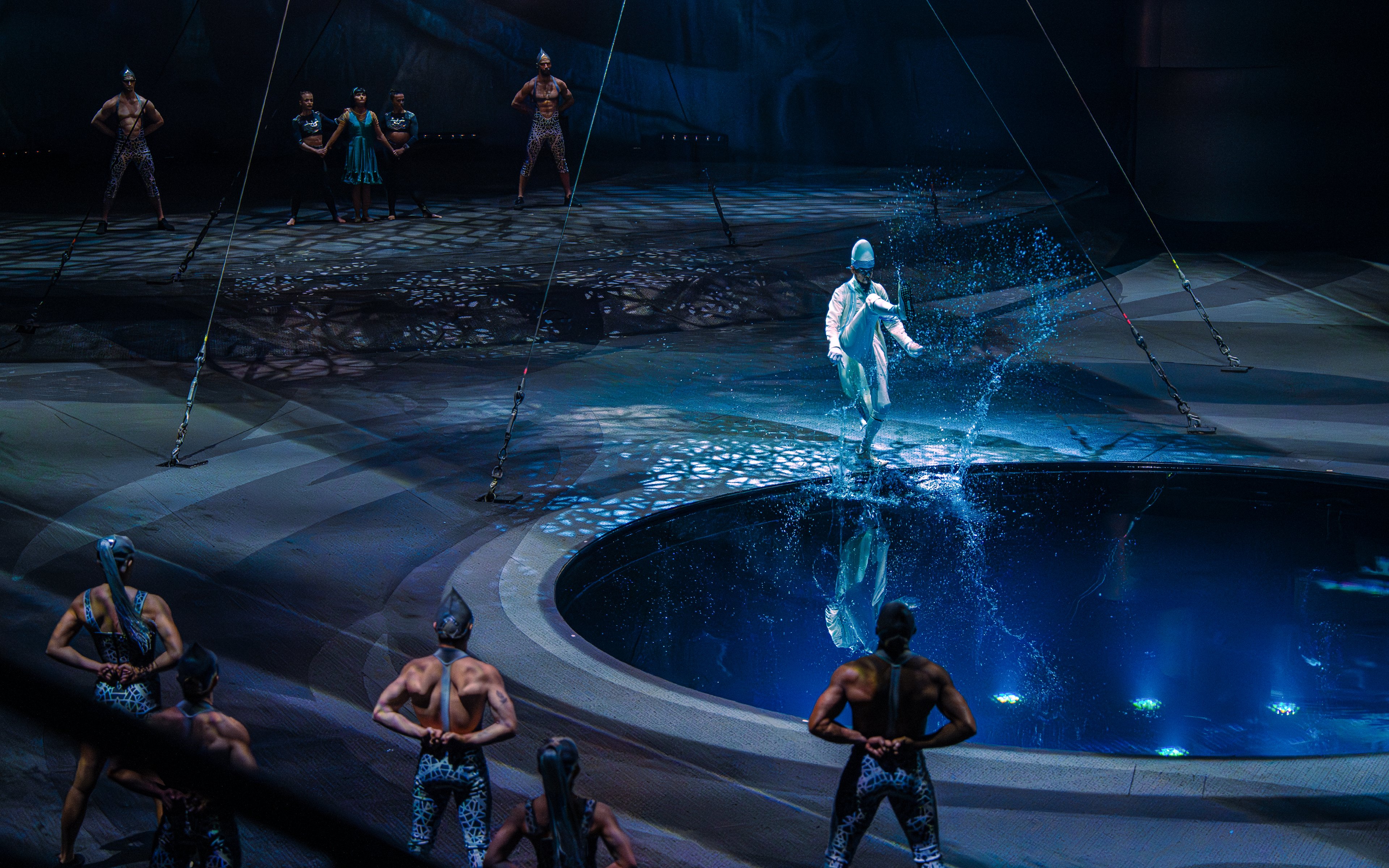 Performer at La Perle show in Dubai walking on water with acrobats in the background.