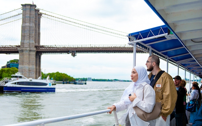 Tourists on a boat tour near the Brooklyn Bridge, New York City.