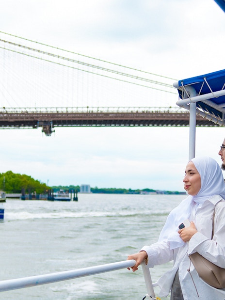 Tourists on a boat tour near the Brooklyn Bridge, New York City.