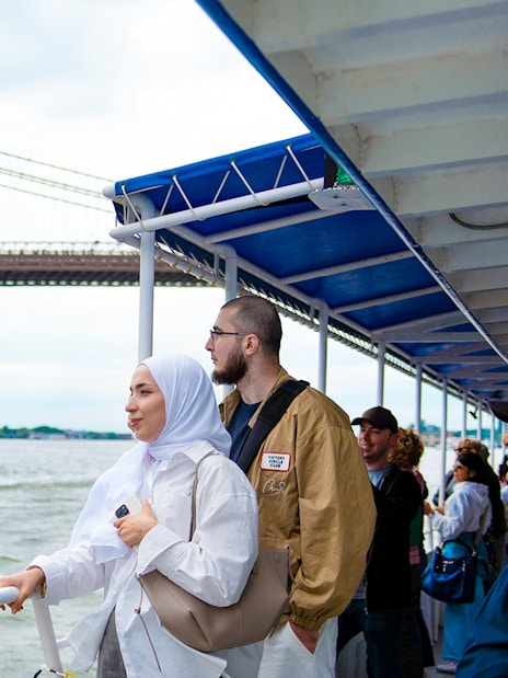 Tourists on a boat tour near the Brooklyn Bridge, New York City.