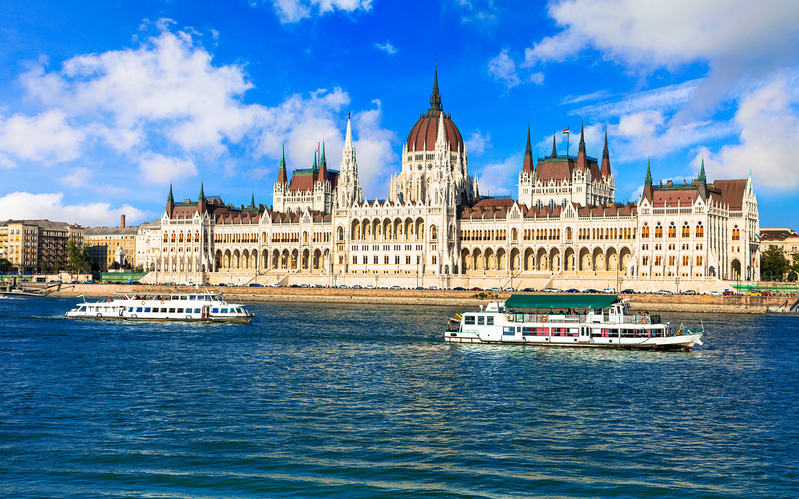Danube River cruise boats passing the Hungarian Parliament Building in Budapest.