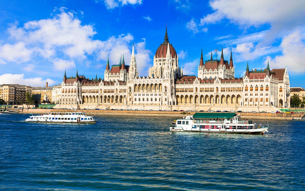 Danube River cruise boats passing the Hungarian Parliament Building in Budapest.