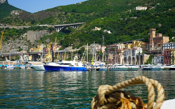 Private boat on Amalfi Coast with Positano's colorful buildings and lush hills in the background.