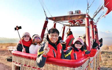 Hot air balloon passengers in Pamukkale preparing for flight with scenic landscape in background.