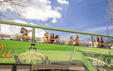 Tourists on Seville hop-on hop-off bus taking photos and enjoying city views.