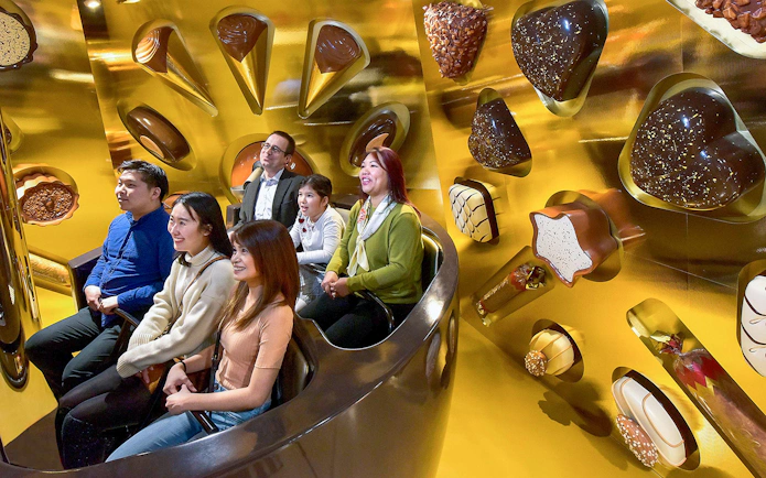 Family enjoying Swiss Chocolate Adventure ride in Lucerne, surrounded by chocolate-themed decor.