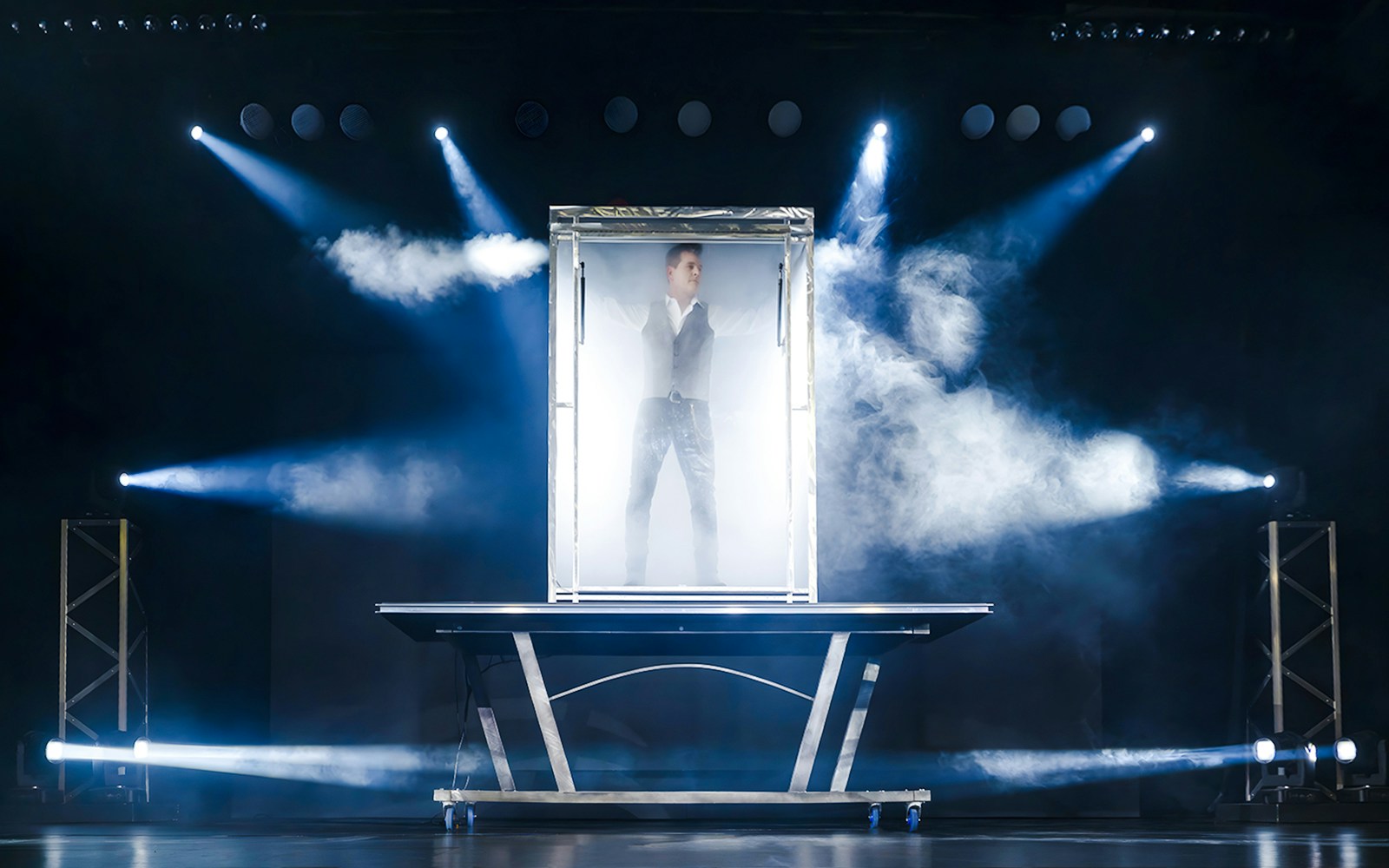 Illusionist performing in a glass box with stage lights at the Evolution Magic Show.