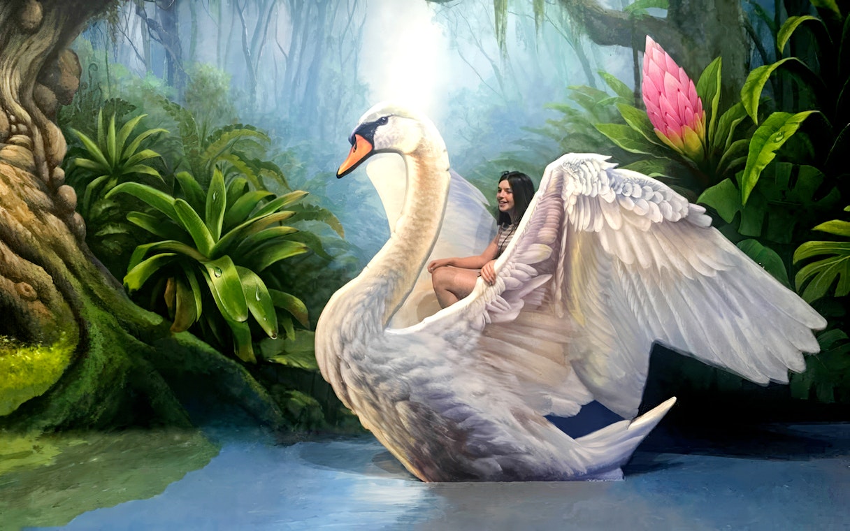 Person posing on a swan illusion at ArtVo Melbourne Trick-Art Gallery.