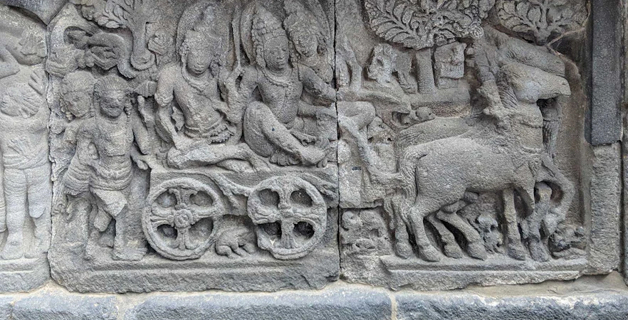 Ancient stone relief at Borobudur depicting a historical scene with figures and animals.