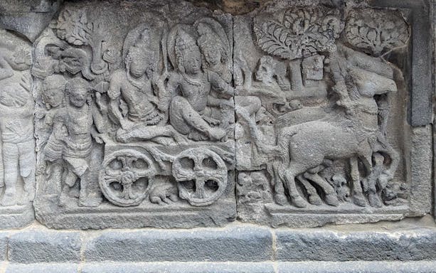 Ancient stone relief at Borobudur depicting a historical scene with figures and animals.