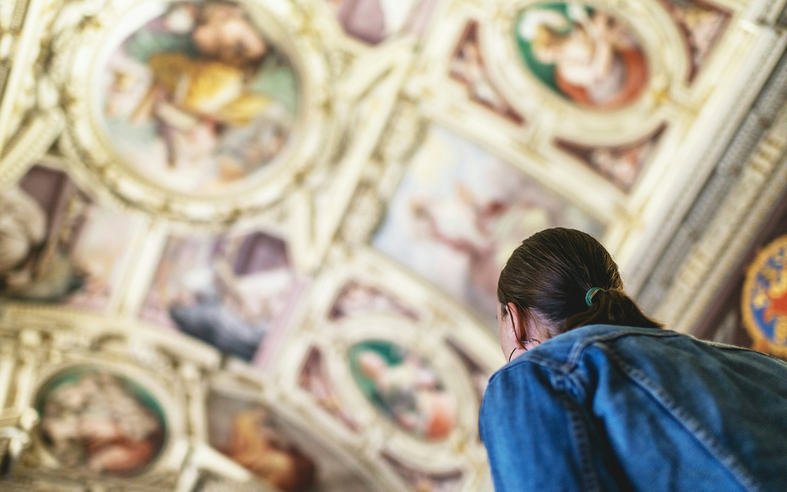 Visitor admiring ceiling artwork in the Vatican Museums.