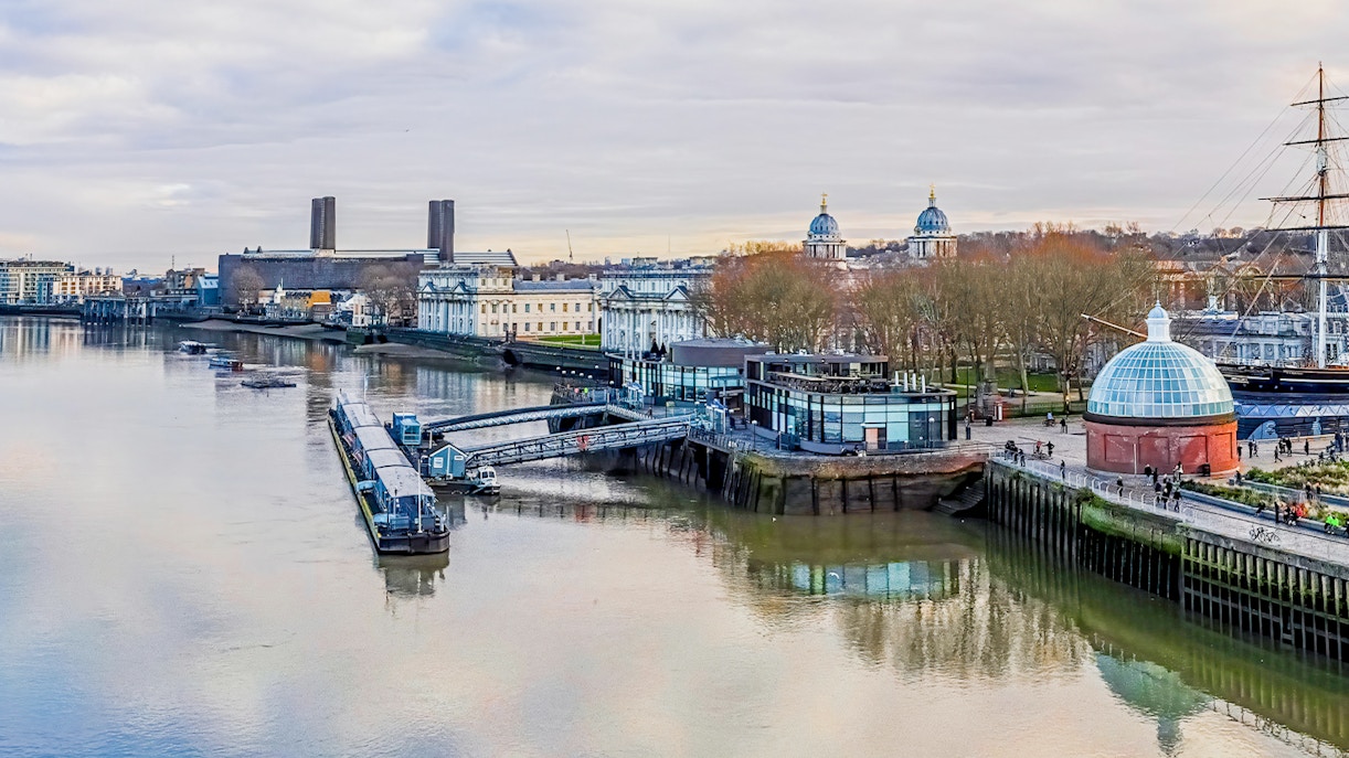 Greenwich Pier on the Thames River with historic buildings and Cutty Sark ship.