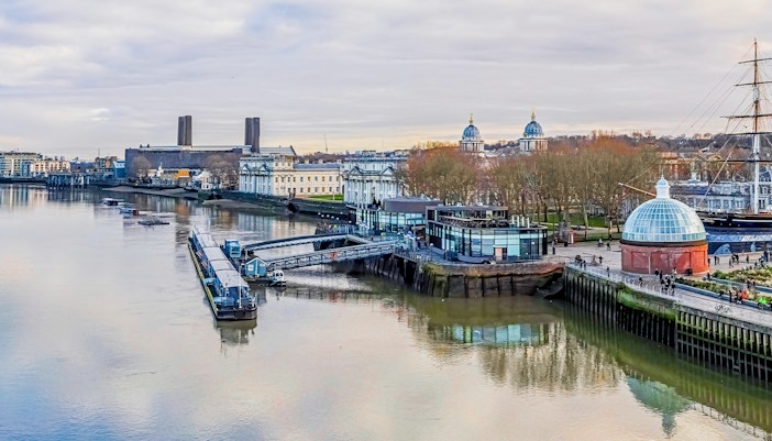 Greenwich Pier on the Thames River with historic buildings and Cutty Sark ship.
