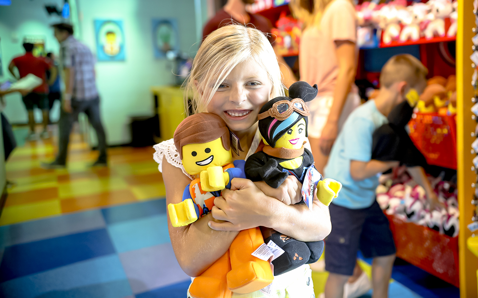 Child holding LEGO plush toys at LEGOLAND® California shop.