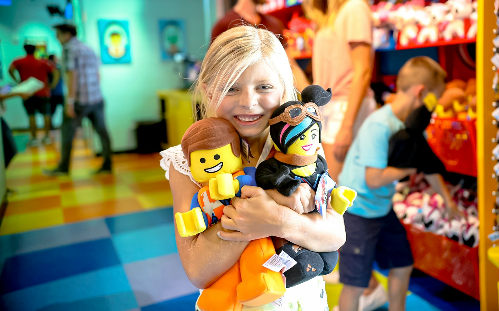 Child holding LEGO plush toys at LEGOLAND® California shop.