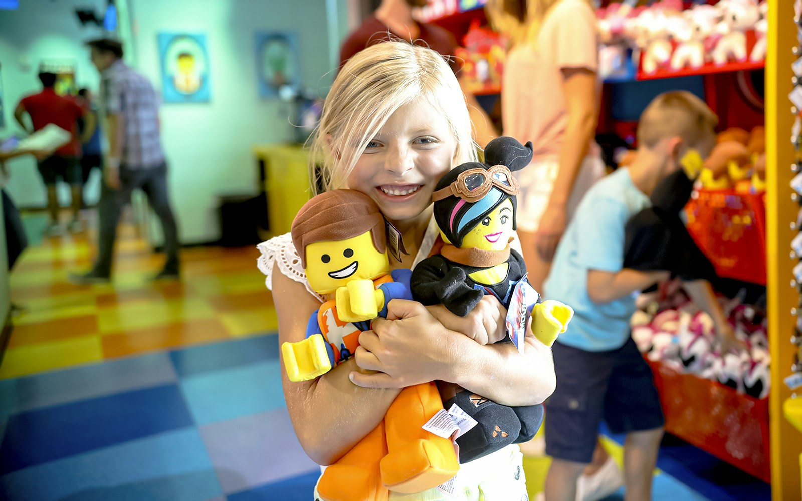 Child holding LEGO plush toys at LEGOLAND® California shop.