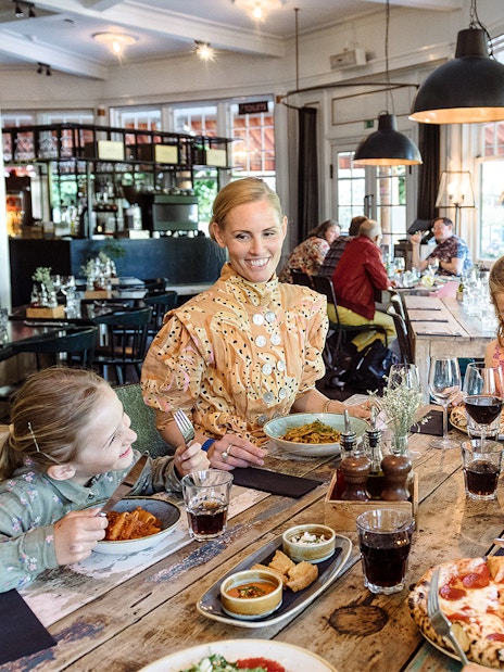 Family dining at a restaurant in Tivoli Gardens, Copenhagen, enjoying pizza and pasta.