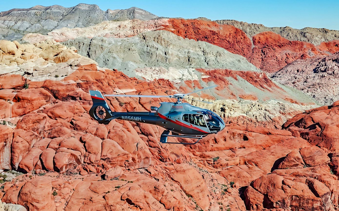 Helicopter flying over Red Rock Canyon's vibrant rock formations near Las Vegas.