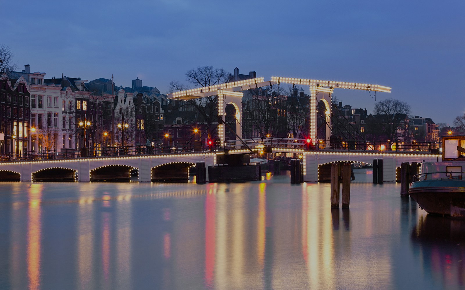 Magere Brug illuminated at night over the Amstel River in Amsterdam.