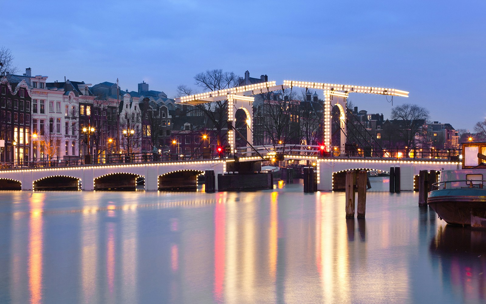 Magere Brug illuminated at night over the Amstel River in Amsterdam.