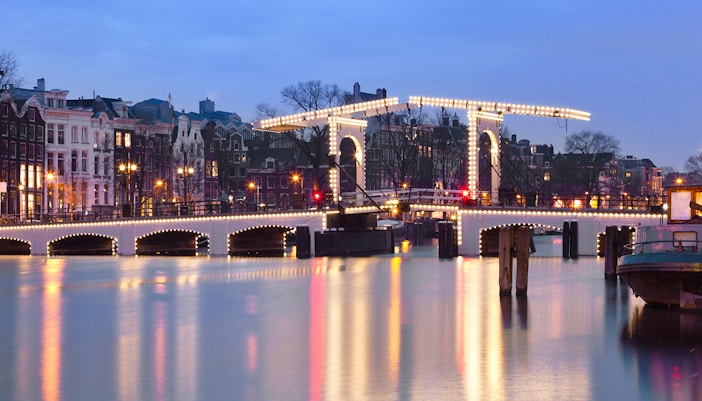 Magere Brug illuminated at night over the Amstel River in Amsterdam.