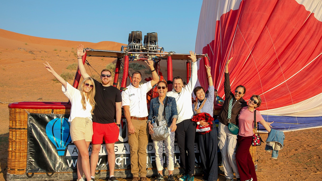 Group of people posing in front of a hot air balloon in Ras Al Khaimah desert.
