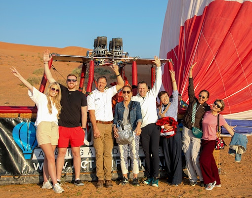Group of people posing in front of a hot air balloon in Ras Al Khaimah desert.