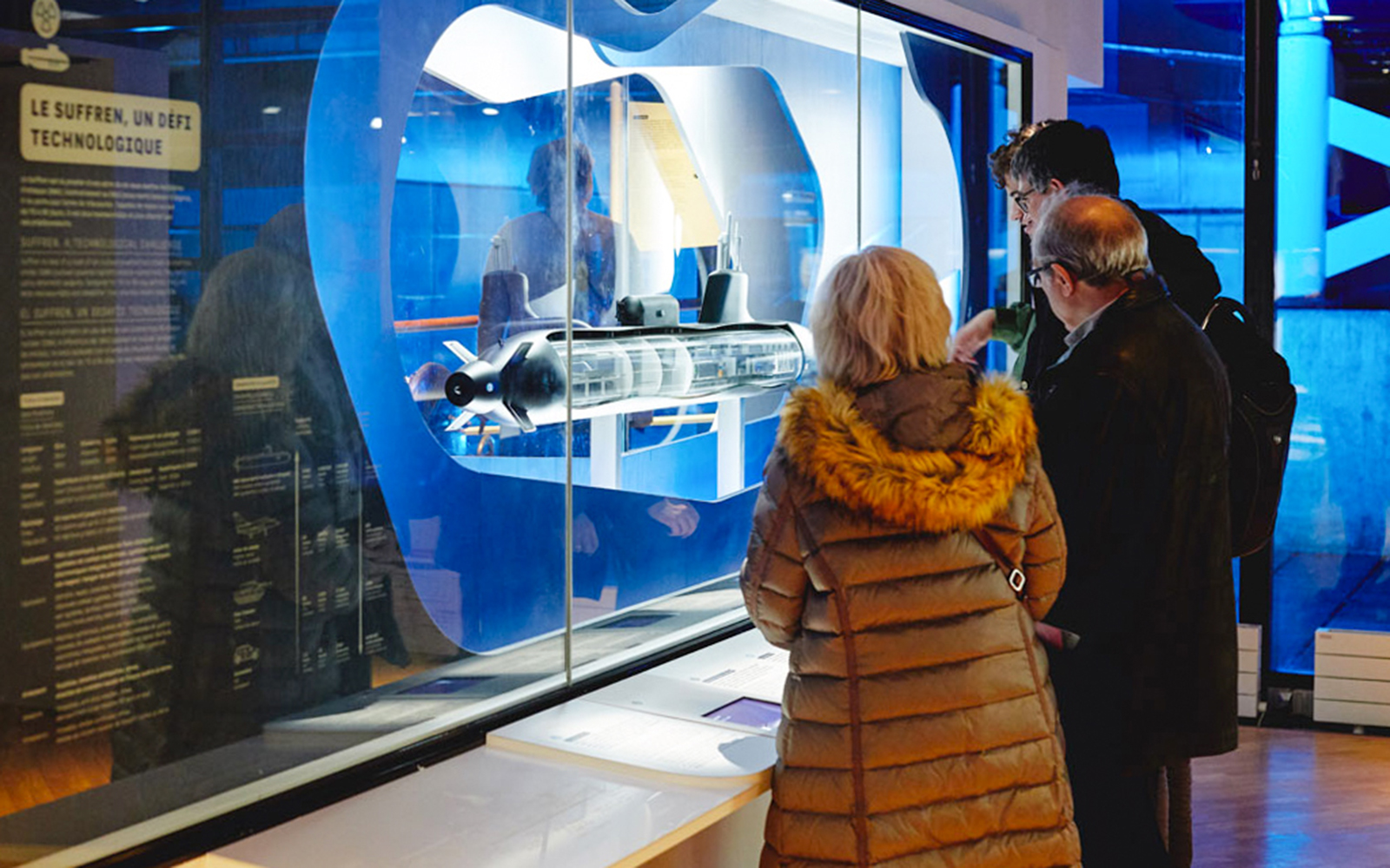 Visitors observing submarine model at Paris technology exhibit.