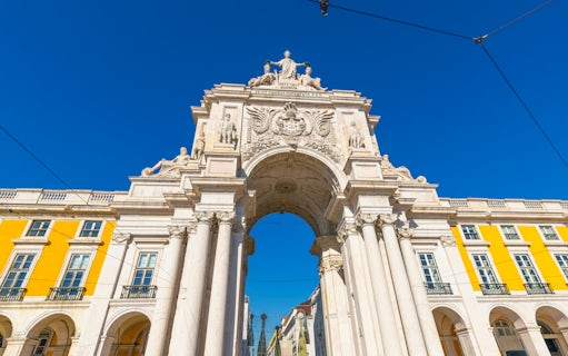 Rua Augusta Arch in Lisbon with detailed sculptures and bright yellow buildings.
