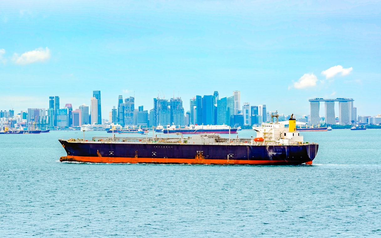 LPG tanker sailing through Singapore Strait with city skyline in background.