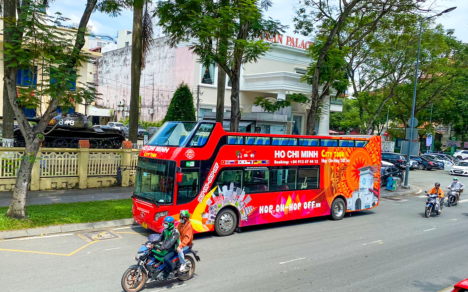 Saigon Hop-on Hop-Off bus passing by Reunification Palace in Ho Chi Minh City.