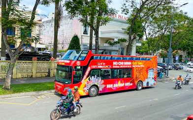 Saigon Hop-on Hop-Off bus passing by Reunification Palace in Ho Chi Minh City.