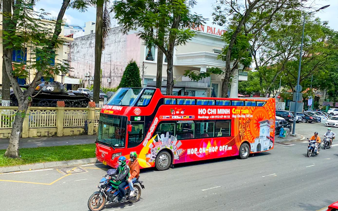 Saigon Hop-on Hop-Off bus passing by Reunification Palace in Ho Chi Minh City.