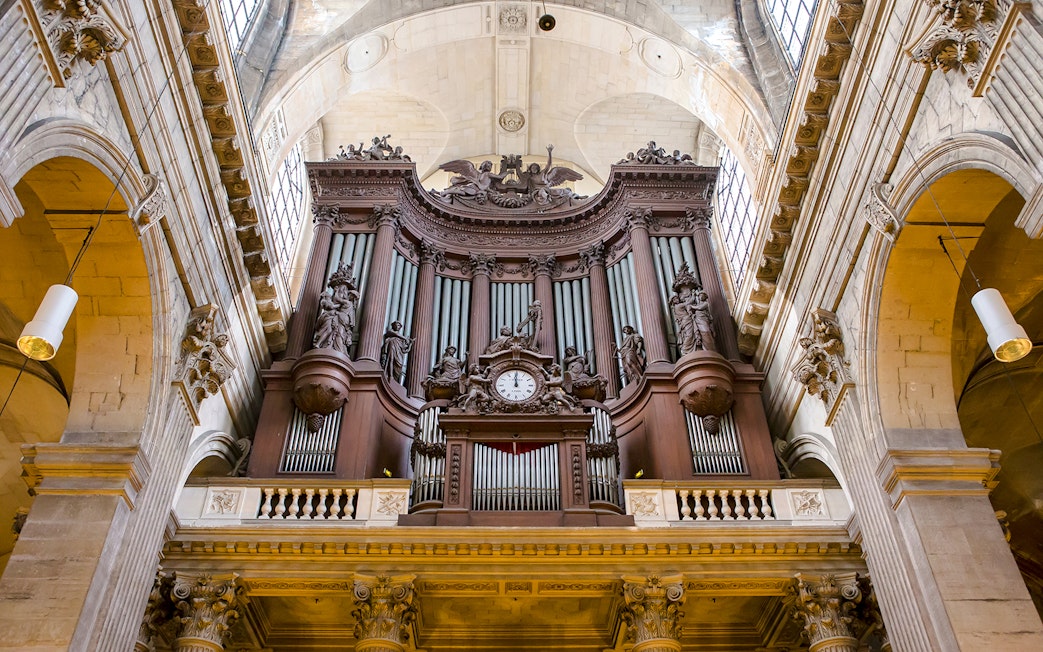 St Sulpice Church interior with ornate pipe organ and detailed sculptures.