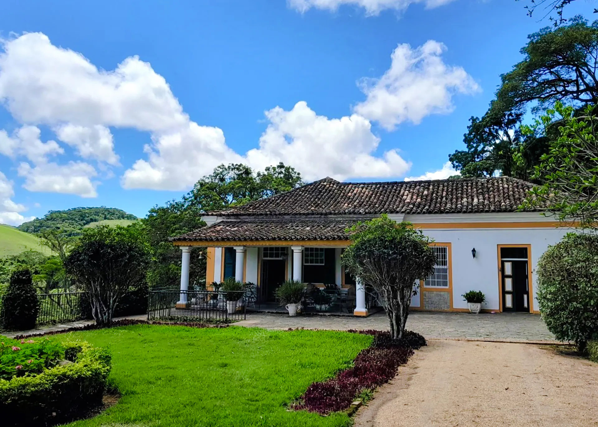 Colonial house in Coffee Valley, Rio de Janeiro, surrounded by lush greenery and hills.
