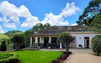 Colonial house in Coffee Valley, Rio de Janeiro, surrounded by lush greenery and hills.