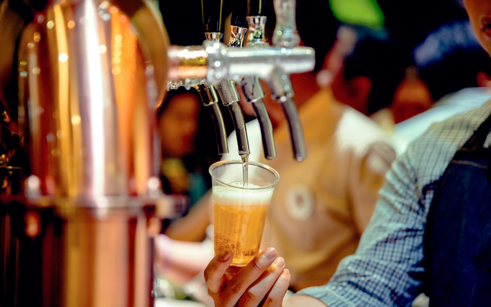 Bartender pouring beer from tap into a plastic cup.