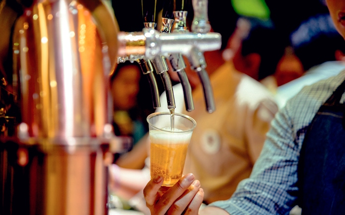 Bartender pouring beer from tap into a plastic cup.