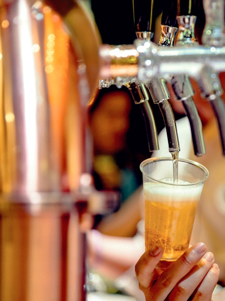 Bartender pouring beer from tap into a plastic cup.