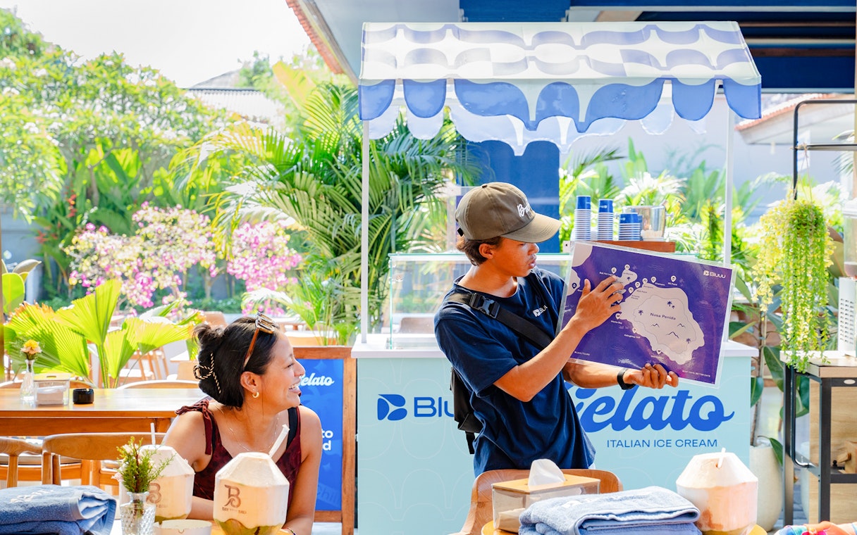 Guide explaining Nusa Penida map to a tourist at a gelato stand.