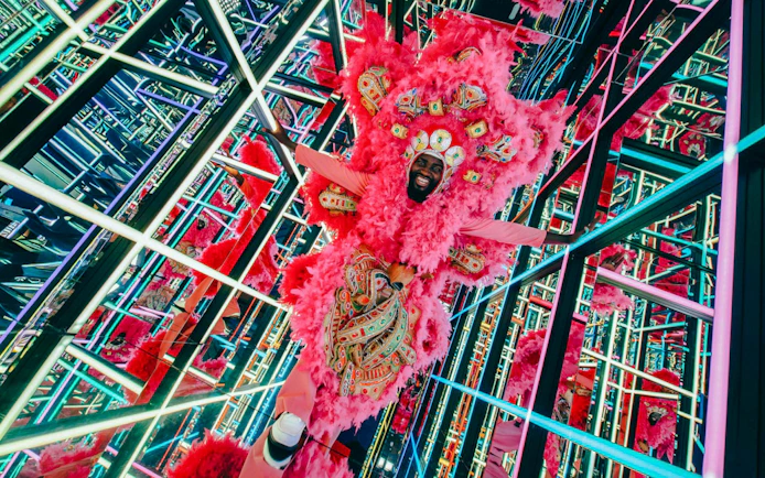 Carnival performer in vibrant pink costume at House of Hype's electric carnival.