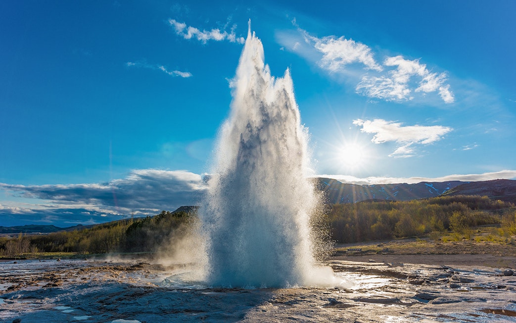 Strokkur geyser erupting under a clear sky in Iceland's Golden Circle tour.
