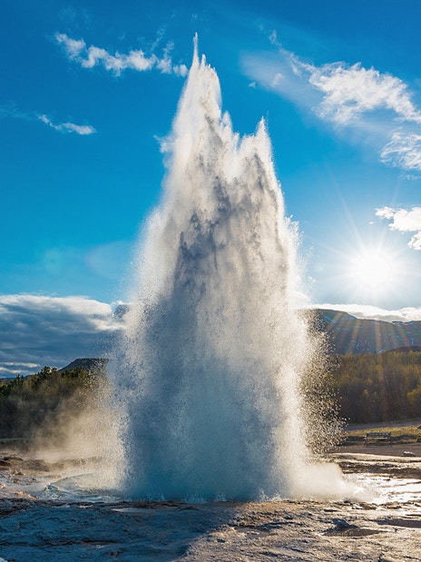 Strokkur geyser erupting under a clear sky in Iceland's Golden Circle tour.