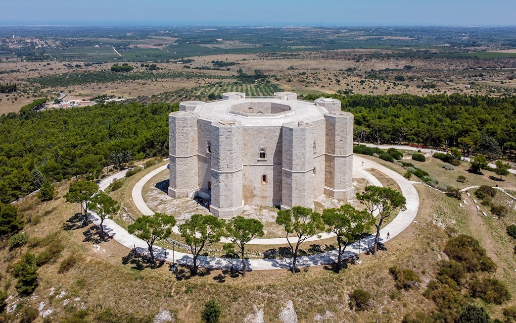 Castel del Monte in Andria, Italy, surrounded by lush greenery and countryside.