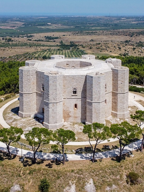 Castel del Monte in Andria, Italy, surrounded by lush greenery and countryside.