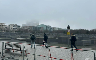 People walking through the Holocaust Memorial in Berlin during a foggy day.