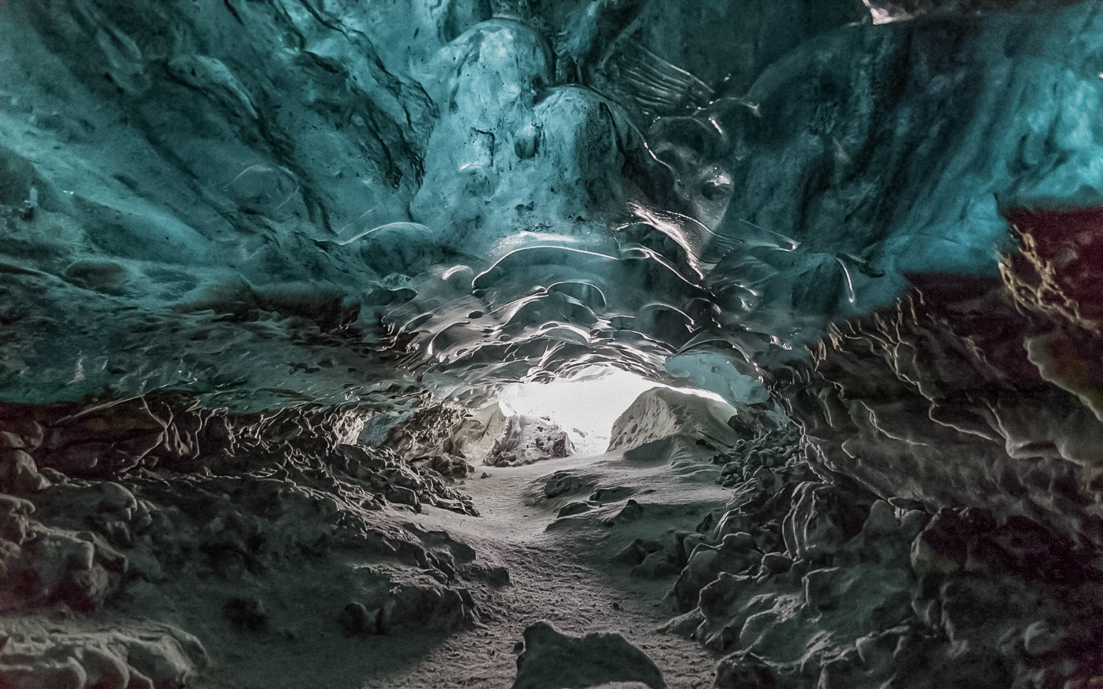 Crystal Ice Cave interior with blue ice formations and a snowy path.