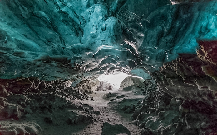 Crystal Ice Cave interior with blue ice formations and a snowy path.