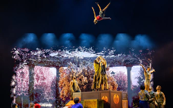 Acrobats performing mid-air flips during Cirque du Soleil Alizé stage show.